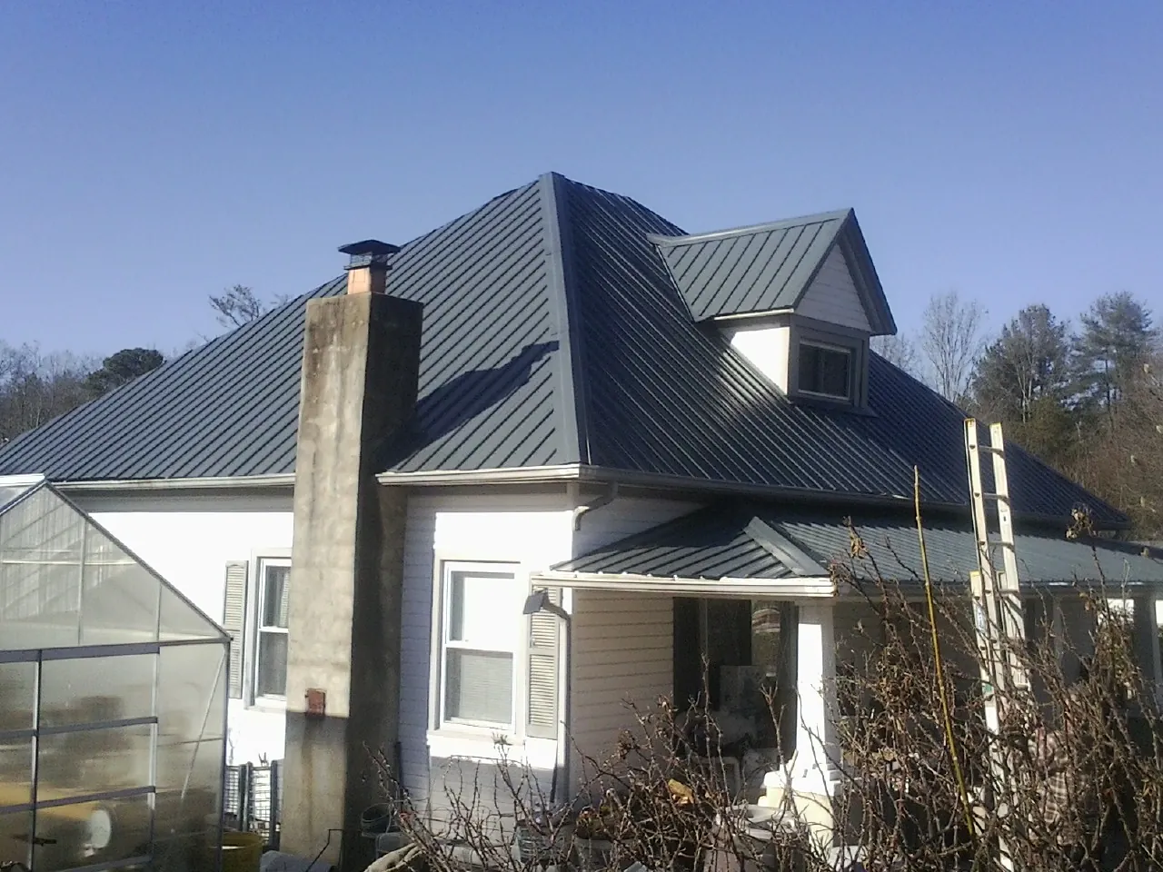Dark blue standing seam metal roof on a white farmhouse with dormer — Slate & Tile Roof Repair by Roofing Brothers in Hunter