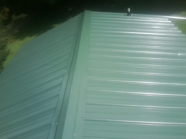 New green metal panels meeting at the ridge of a roof — Flat Roof Repair work by our crew in Hunter
