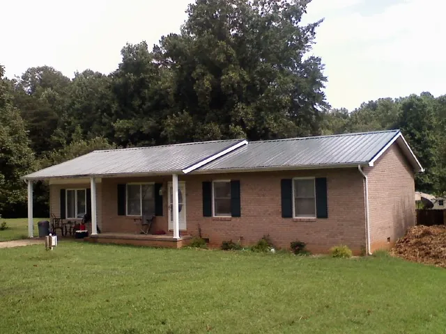 Gray metal roof on a brick ranch house with a side carport in Hunter