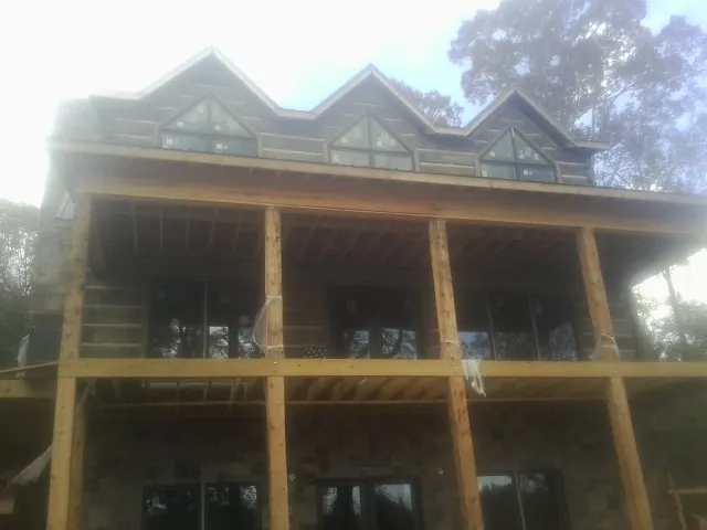 Dormers and porch framing on a large log home under construction — Roof Coating work by our crew in Hunter